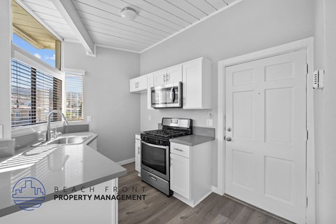 A kitchen with white cabinets and a stove top oven.