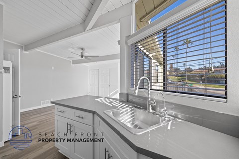 A modern kitchen with a stainless steel sink and a ceiling fan.