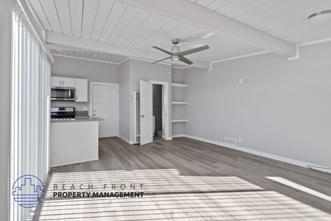 A spacious room with a ceiling fan and a rug on the floor.