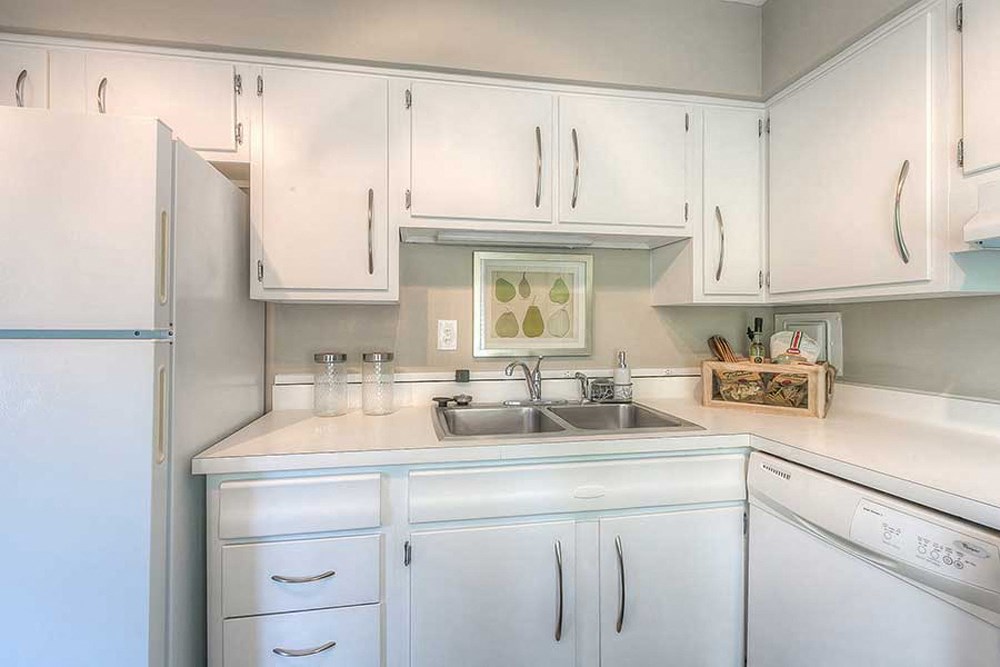 a white kitchen with white cabinets and a sink