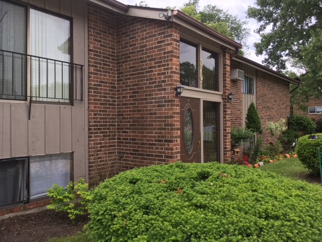the front of a brick house with a yard and a glass door