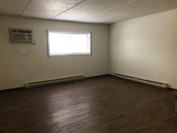 an empty room with a window and a wooden floor