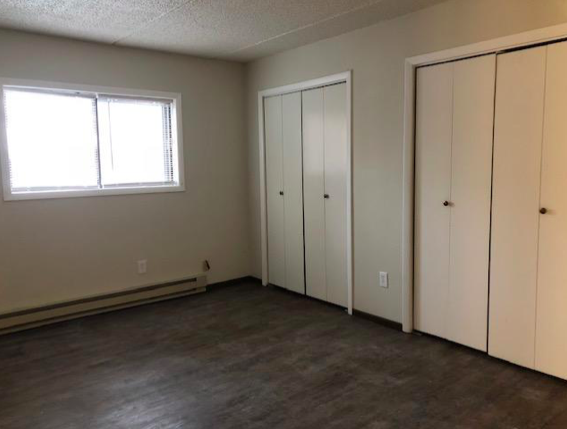 an empty living room with white cabinets and a window