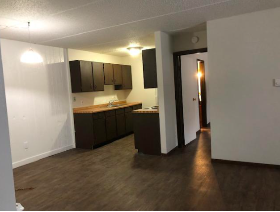 an empty living room and kitchen with a wood floor
