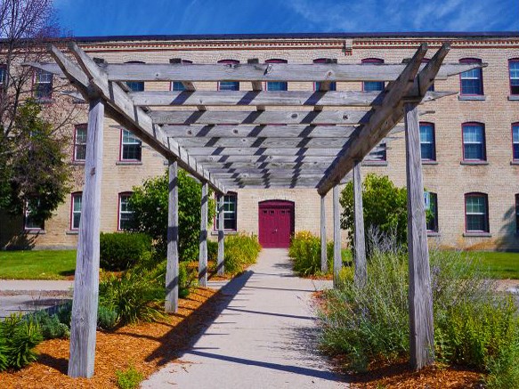 a covered walkway in front of a building with a red door