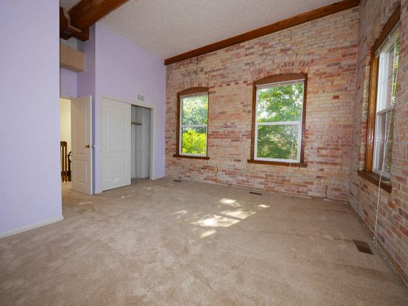 an empty room with a brick wall and two windows