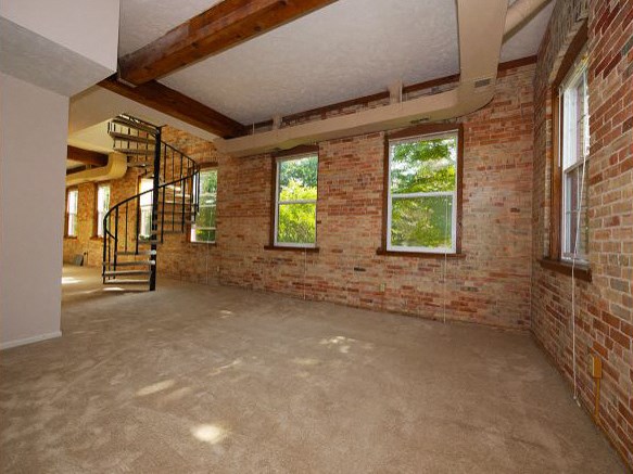 an empty brick room with a spiral staircase
