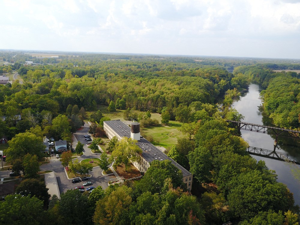 an aerial view of a building surrounded by trees and a river