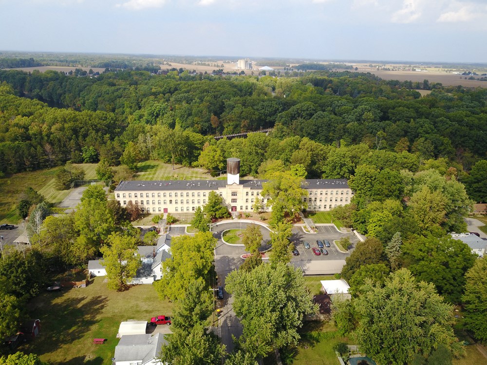 an aerial view of a large white building surrounded by trees