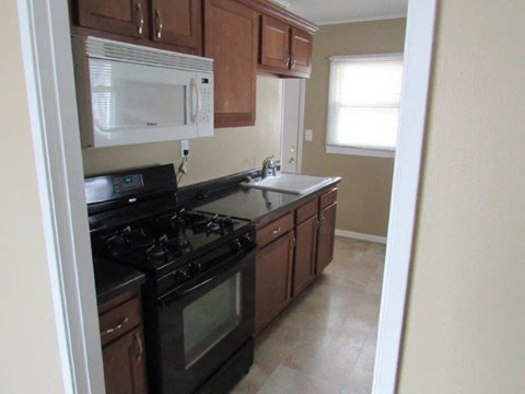 A kitchen with black appliances and wooden cabinets.