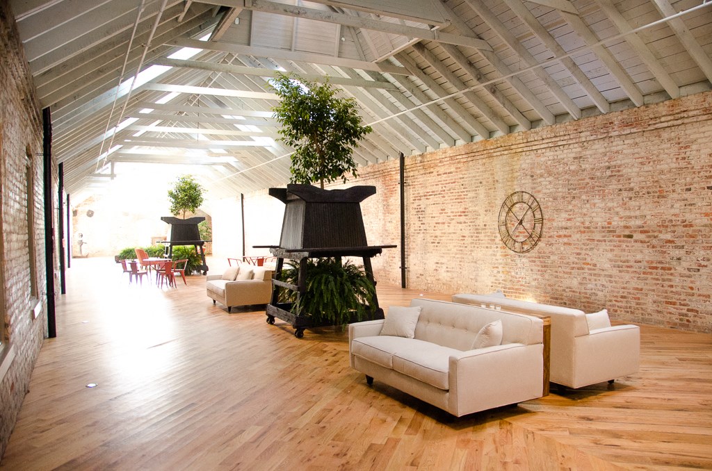 a living room with white furniture and a brick wall