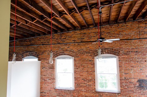 a brick room with a ceiling fan and two windows