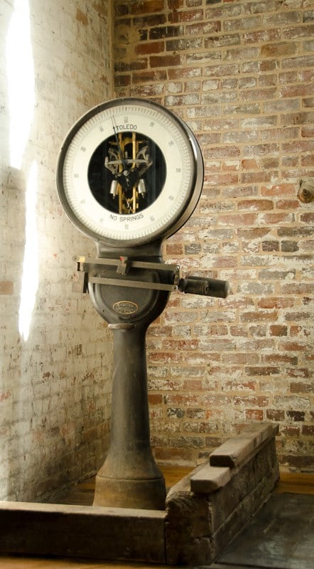 a clock on a pole next to a brick wall