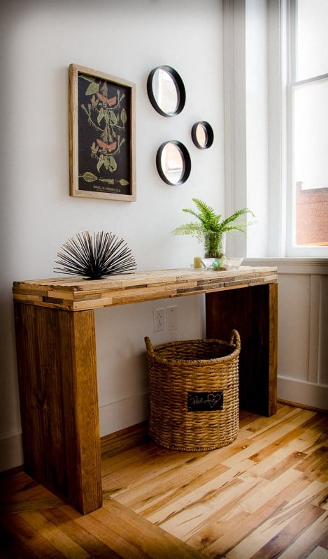 a console table with a basket in a room with a window