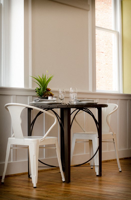 a small table with two white chairs and a plant