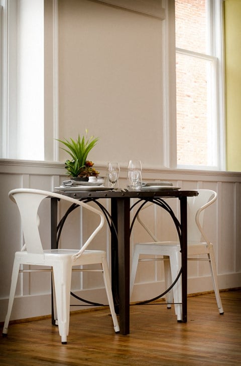 a small table with two white chairs and a plant