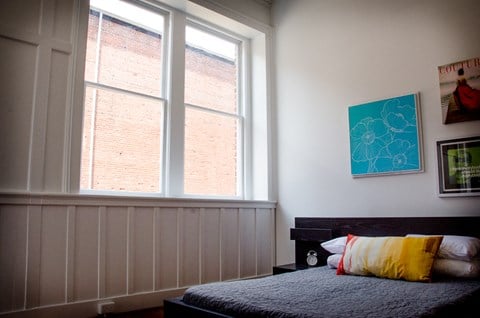 a bedroom with a bed and two large windows
