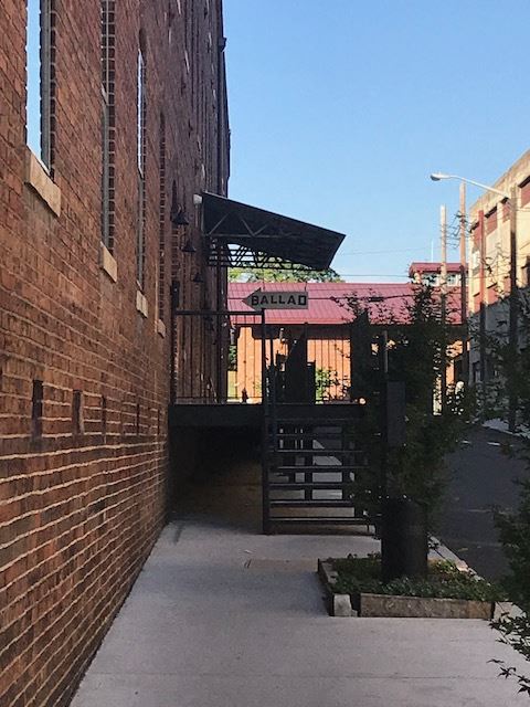 an alleyway between two brick buildings with a gate