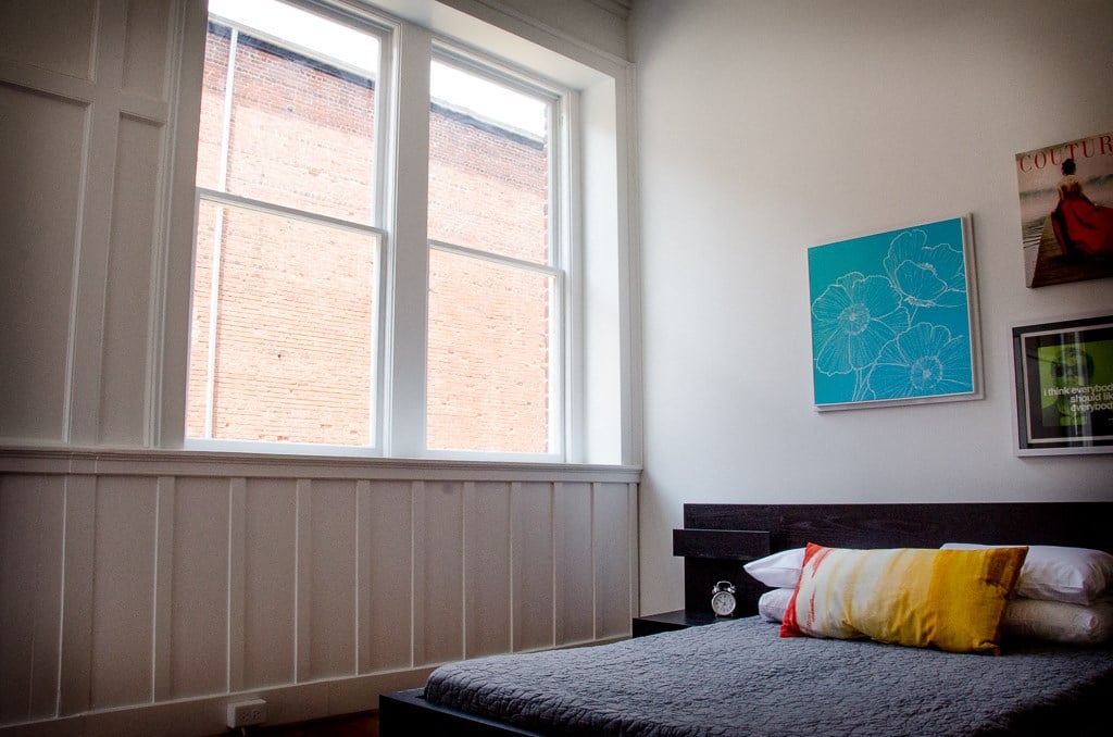 a bedroom with a bed and two large windows