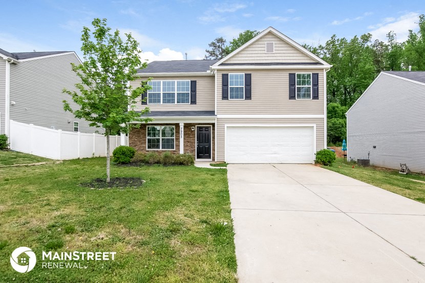 a beige house with a white garage door and a lawn