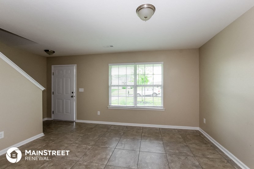 the spacious living room with tile flooring and a white door