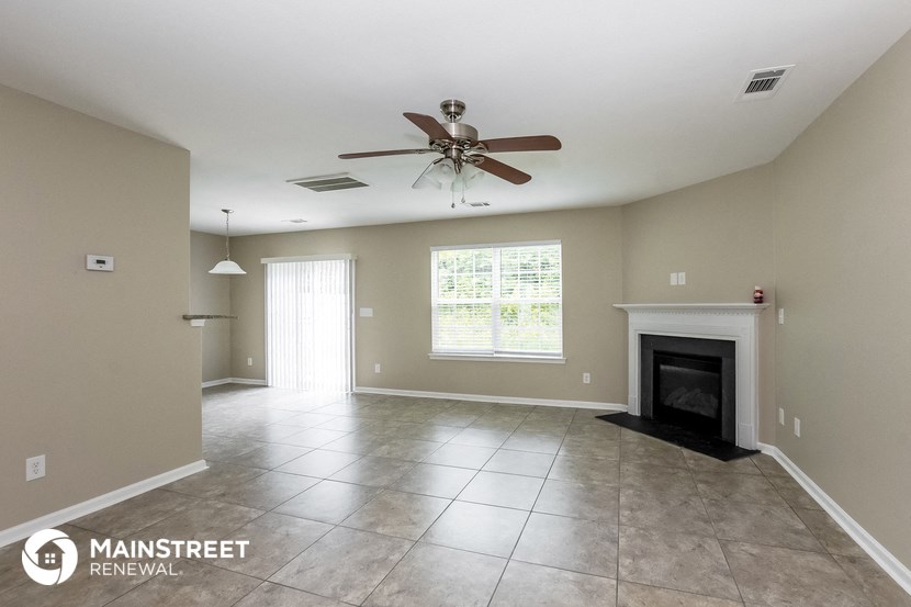 a large living room with a fireplace and a ceiling fan