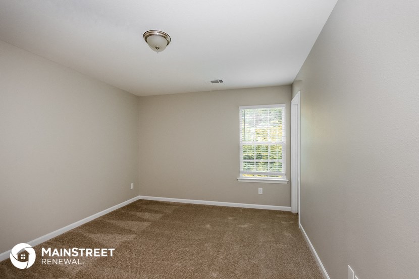 the upstairs bedroom with carpeted flooring and a window