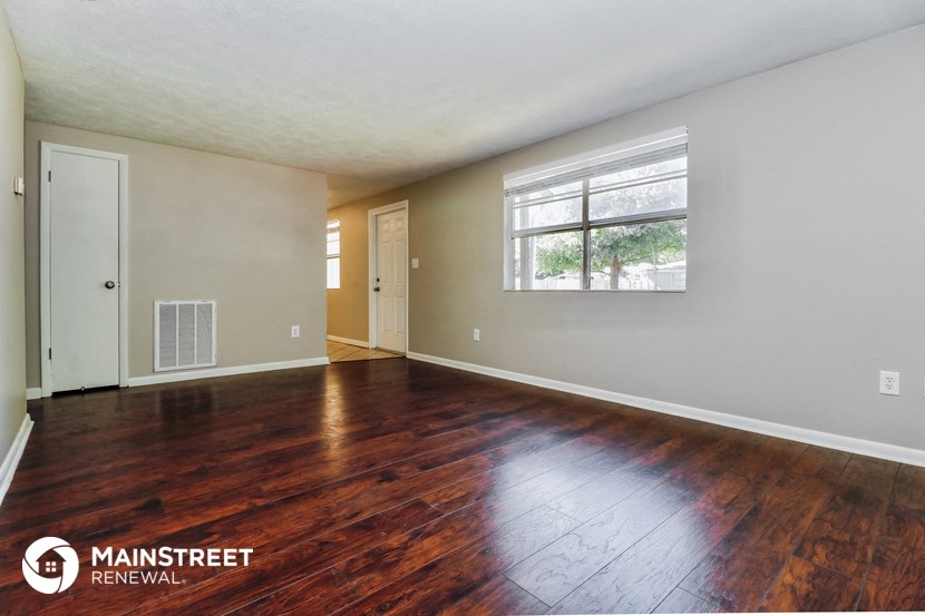 the living room of a house with wood floors and a window