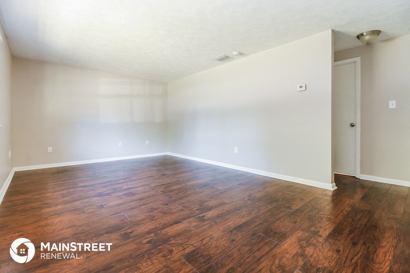 the spacious living room with hardwood flooring and white walls