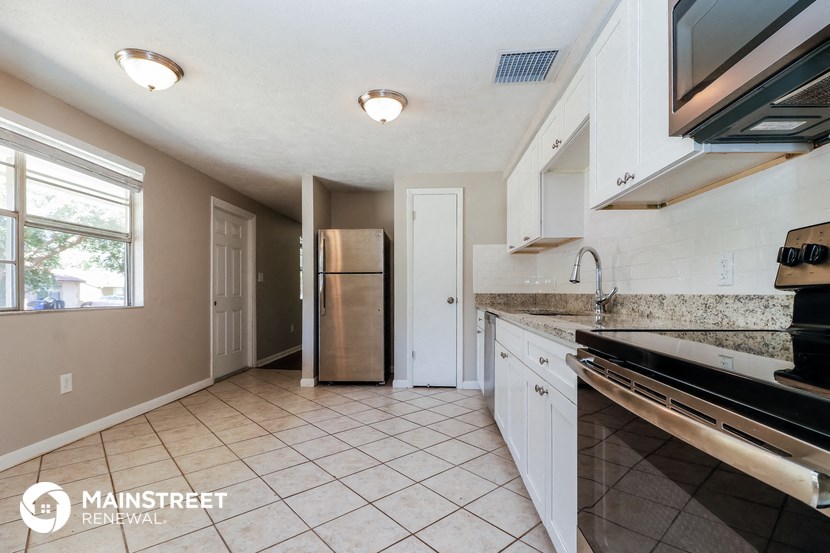 a kitchen with white cabinets and a stainless steel refrigerator