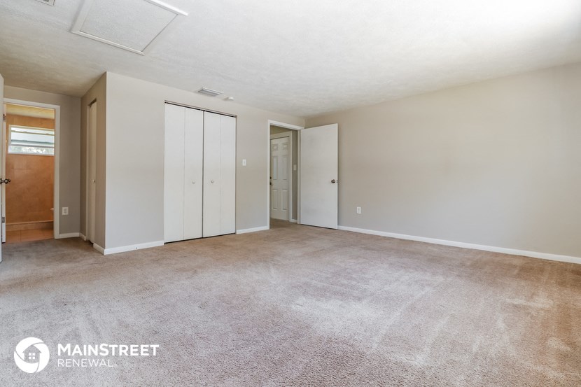 a spacious living room with carpet and white walls
