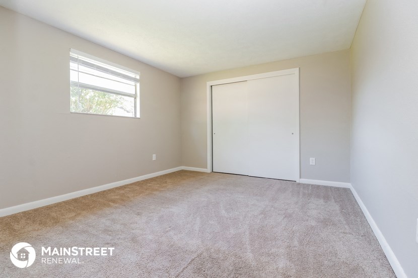 a room with carpet and a white door and a window