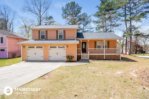 a pink house with a garage and a porch and a driveway