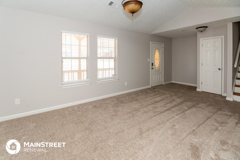 the living room of an empty house with carpet and two windows