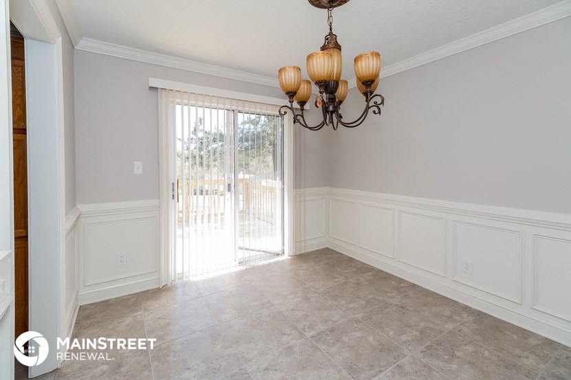 a dining room with white wainscoting and a chandelier