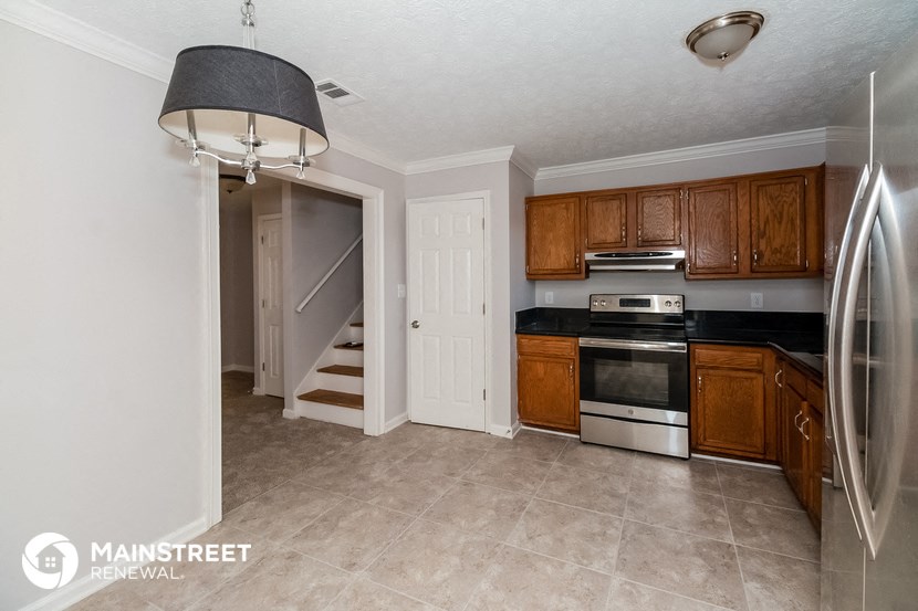 a kitchen with wooden cabinets and stainless steel appliances and a staircase
