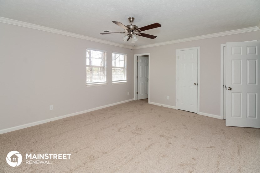 the master bedroom has a carpeted floor and a ceiling fan