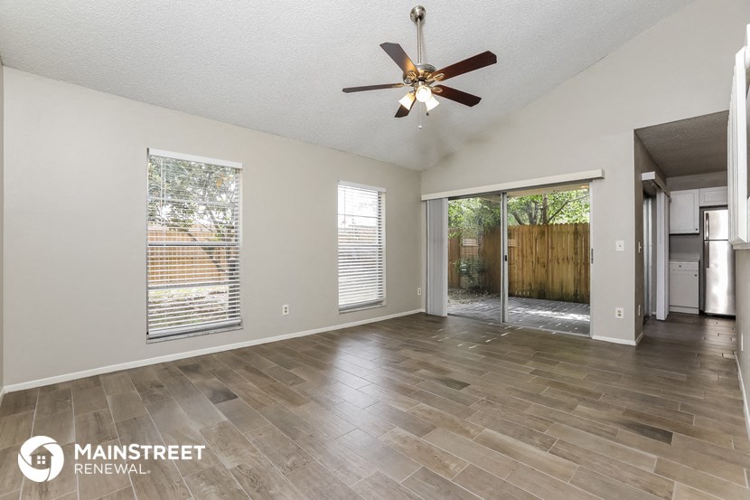 an empty living room with a ceiling fan and a sliding glass door