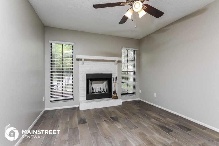 a living room with a fireplace and a ceiling fan