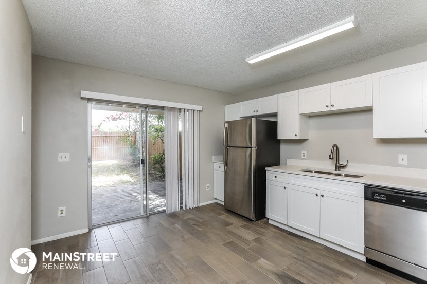 a kitchen with white cabinets and a stainless steel refrigerator