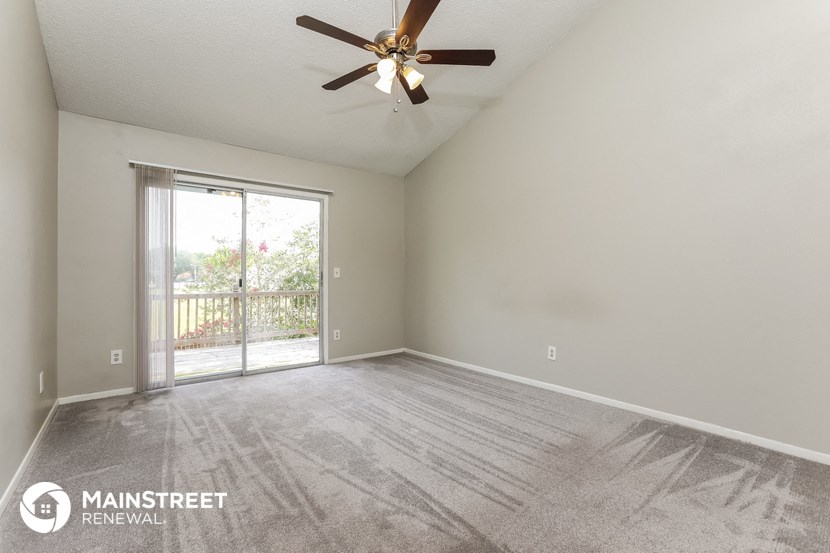 an empty living room with a ceiling fan and a sliding glass door