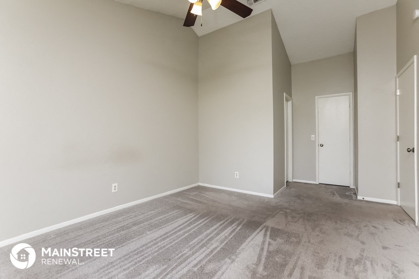 the spacious living room with a ceiling fan and gray vinyl flooring