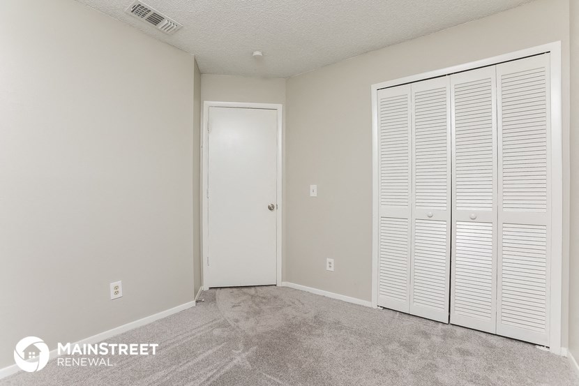a bedroom with two closet doors and a door to the bathroom