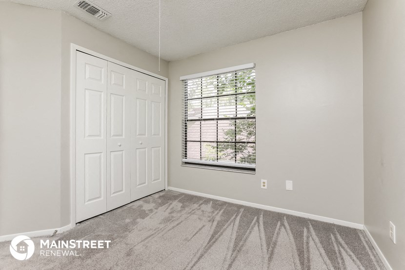 the bedroom of a home with a large window and a white door