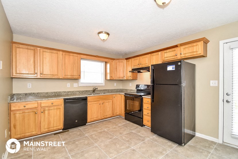 a kitchen with wooden cabinets and a black refrigerator