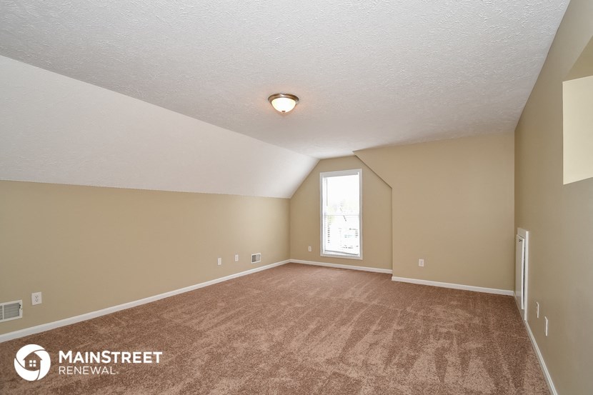 the spacious living room with carpeting and a window