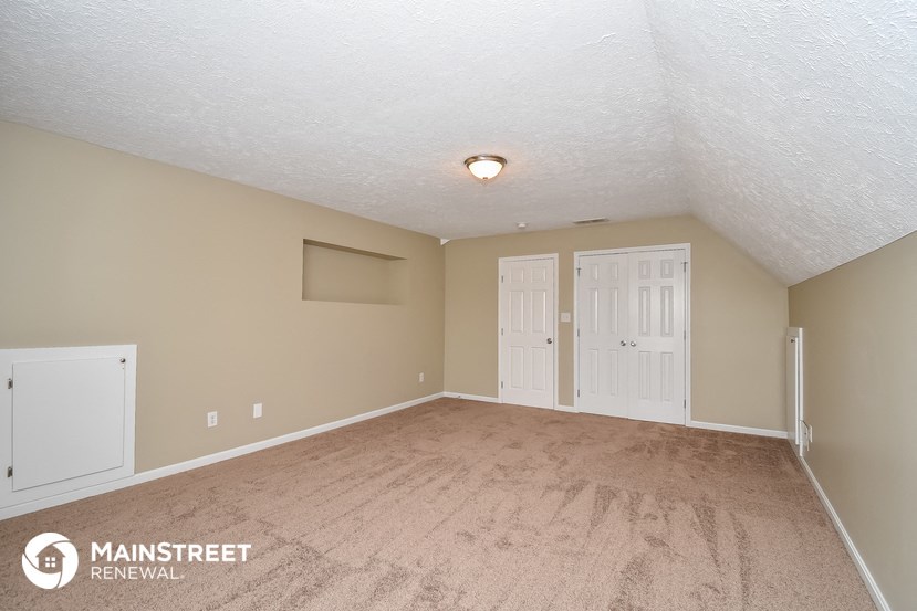 the spacious living room with carpeted floors and white doors