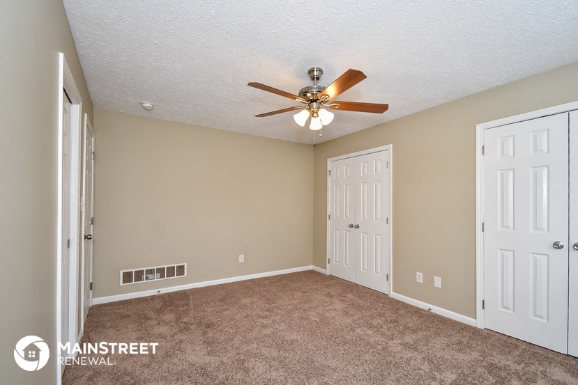 the master bedroom has a carpeted floor and a ceiling fan