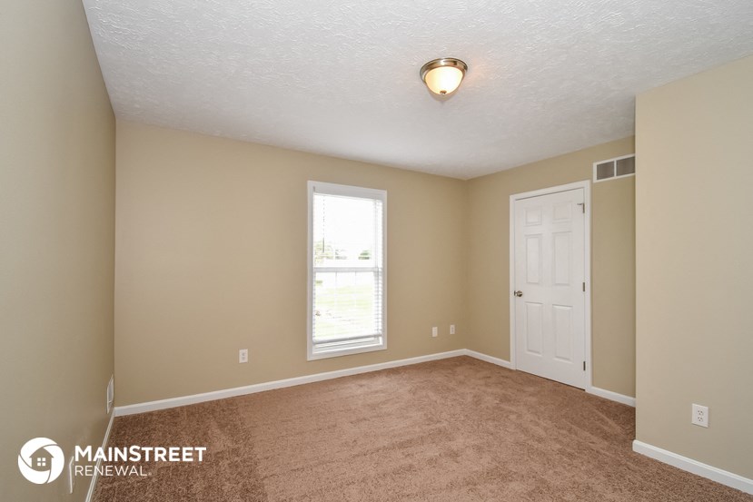 the spacious living room with beige carpet and a white door