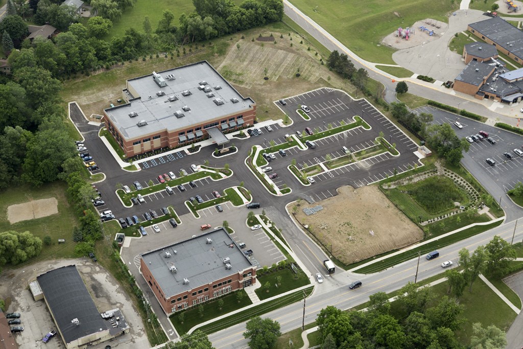 An aerial view of a parking lot with a building in the background.